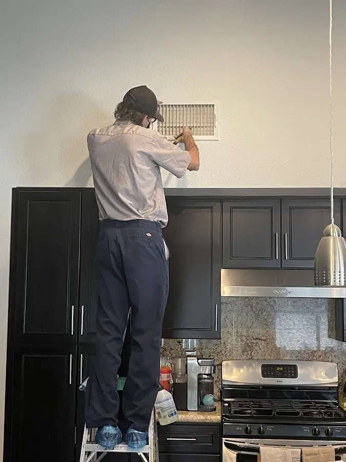 Technician inspecting an air vent during HVAC service in Closter